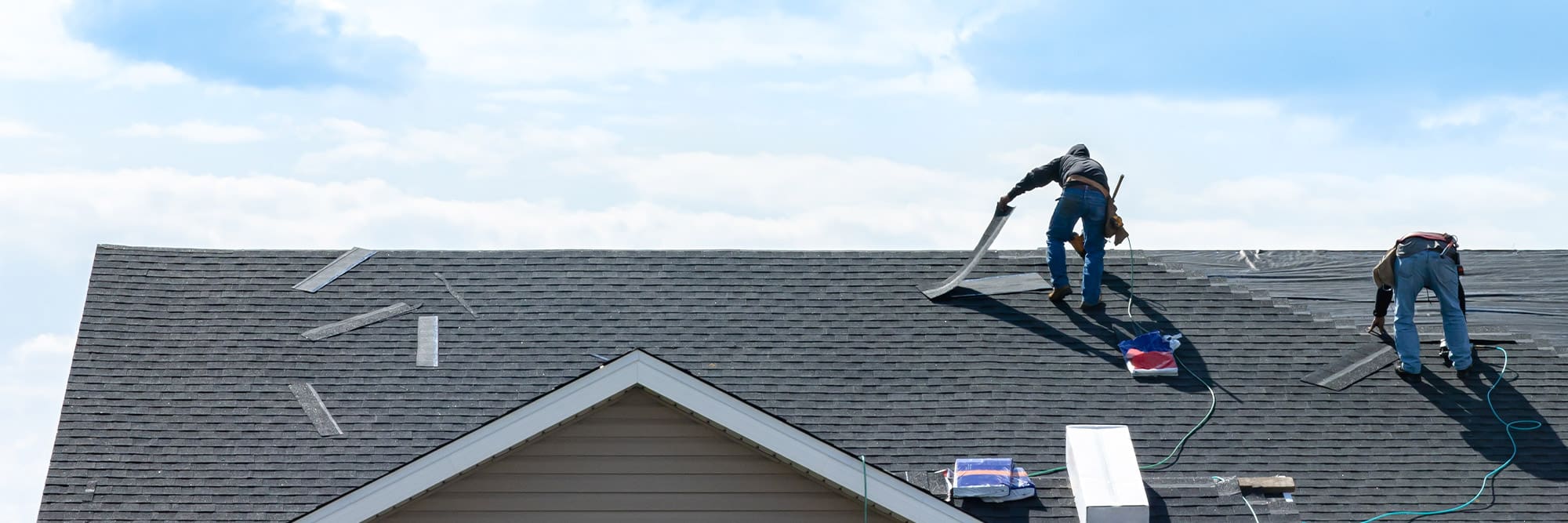 construction workers fixing roof against clouds blue sky, install shingles